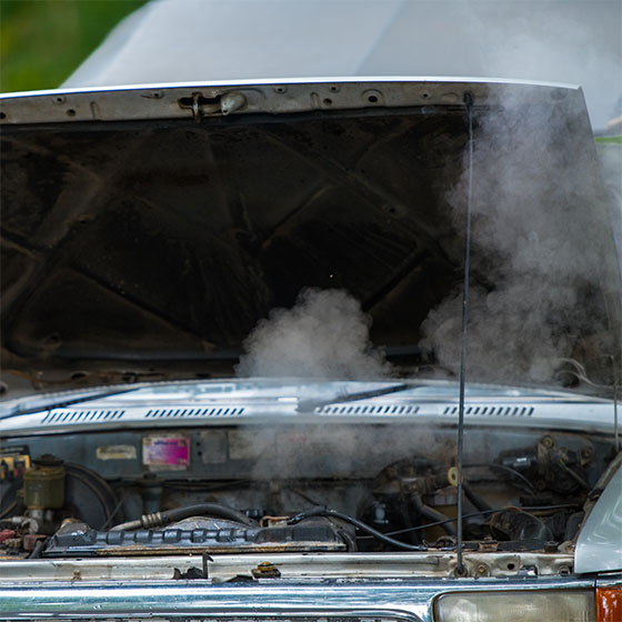 Broken down car with smoking engine, overheating engine on the road.