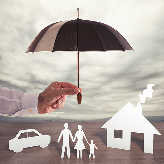 Man holding umbrella over paper cutouts of car, family, and house